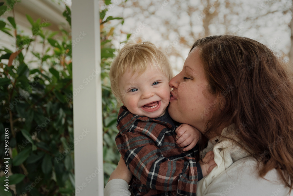 Close-up of mother kissing happy son's cheek in porch Close-up of mother kissing happy son's cheek in porch
