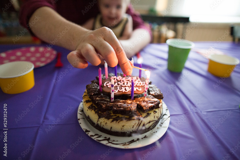 Midsection of father burning birthday candle with son at home