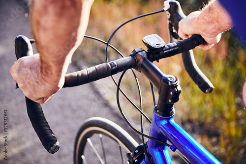 Cropped hands of senior man holding bicycle's handlebar while riding on road photo