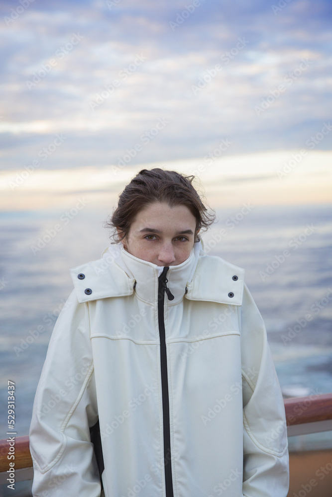 Portrait of woman in warm clothing standing against sea during sunset Portrait of woman in warm clothing standing against sea during sunset
