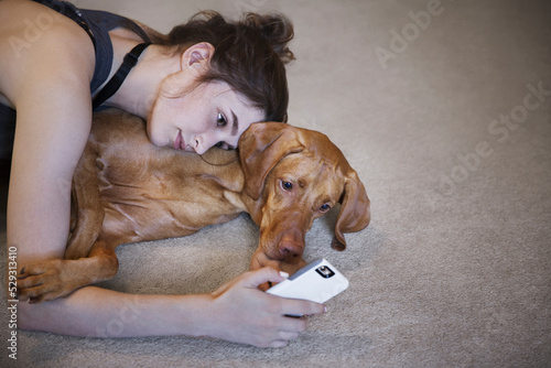 High angle view of woman with dog taking selfie while lying on rug at home photo