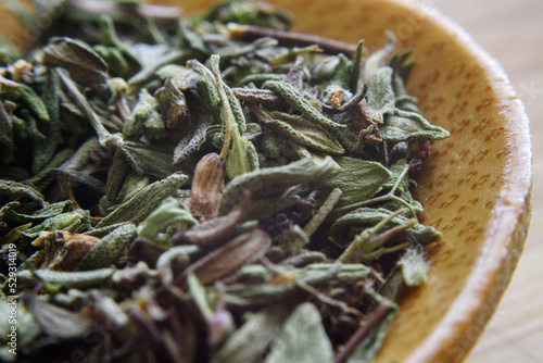 Close-up of dry herbs in wooden spoon on table photo
