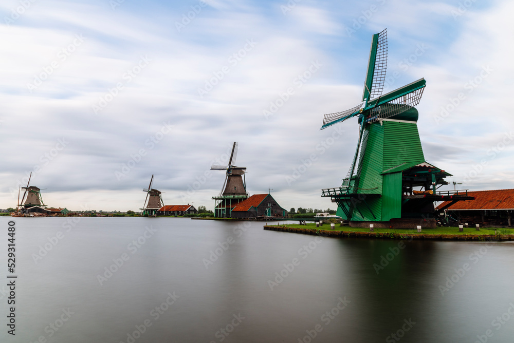 Traditional windmills by canal against cloudy sky Traditional windmills by canal against cloudy sky