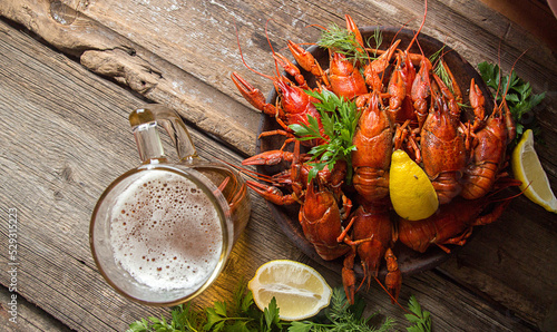 Overhead view of boiled crayfish served with beer on wooden table photo