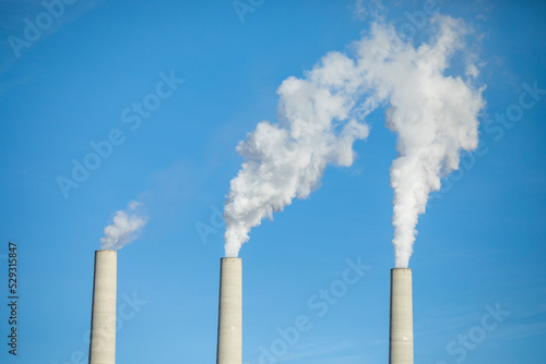 Low angle view of smoke emitting from chimneys against clear blue sky photo