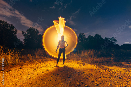 Full length of woman standing against light painting on field at night photo