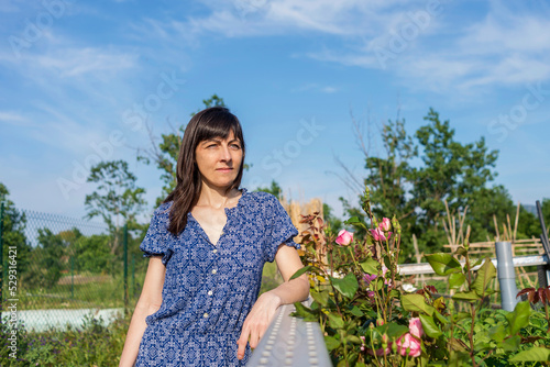 Mature woman wearing blue dress looking at view while standing at farm during sunny day photo