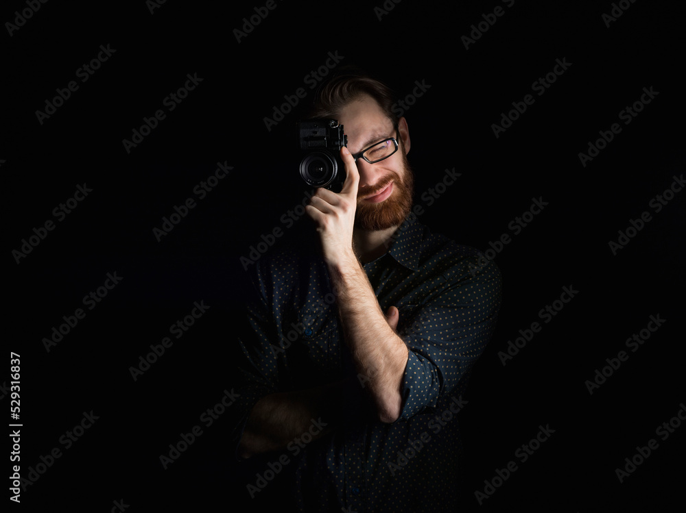 Man photographing with camera while standing against black background Man photographing with camera while standing against black background