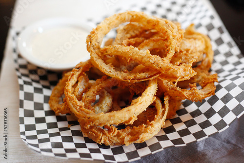 High angle close-up of fried onion rings with dip served in plate on table photo