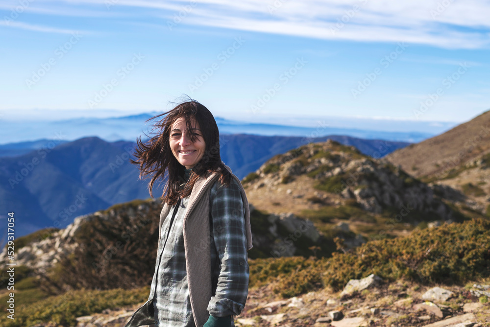 Portrait of smiling woman standing on mountain against blue sky during sunny day Portrait of smiling woman standing on mountain against blue sky during sunny day