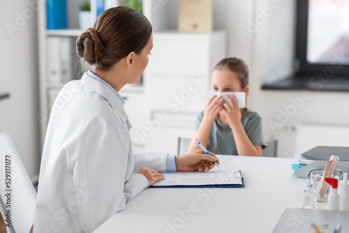 medicine  healthcare and pediatry concept - female doctor or pediatrician and little girl patient blowing her nose on medical exam at clinic