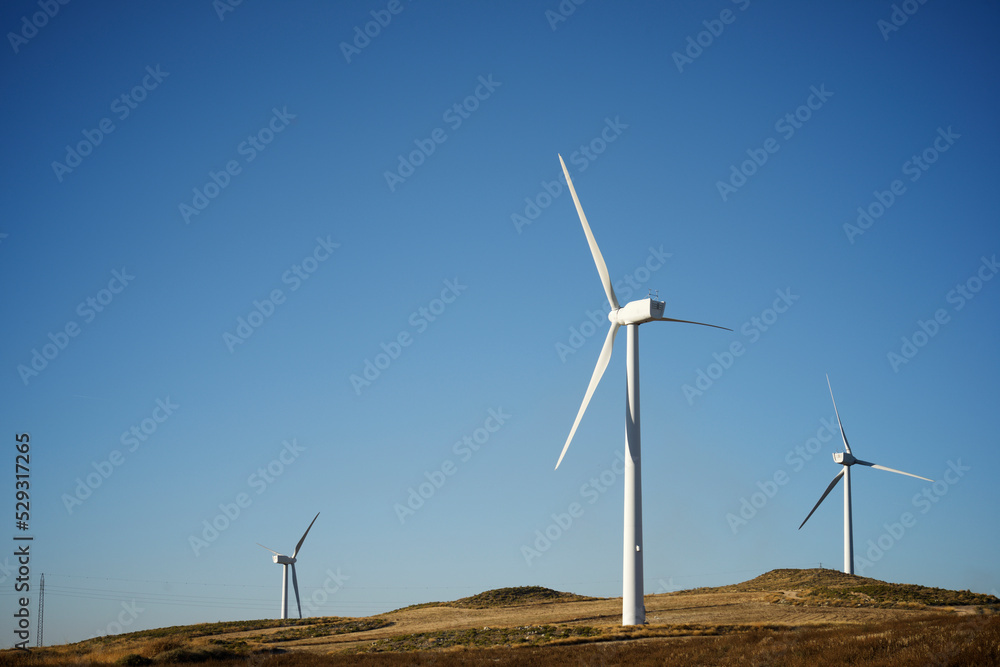 Windmills on land against clear blue sky Windmills on land against clear blue sky