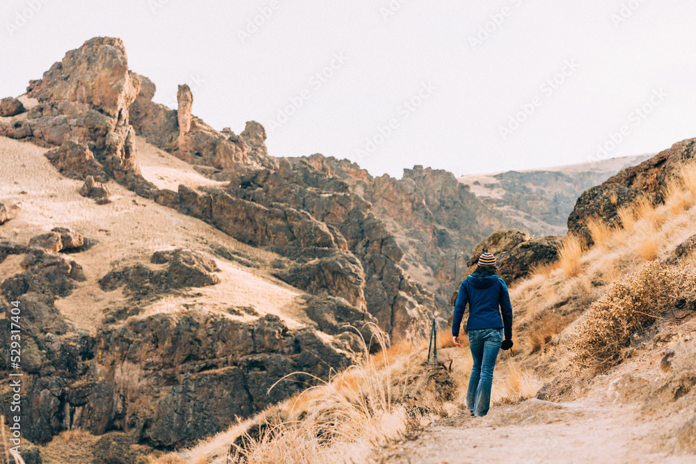 Woman hiking on dirt path in rocky landscape Woman hiking on dirt path in rocky landscape