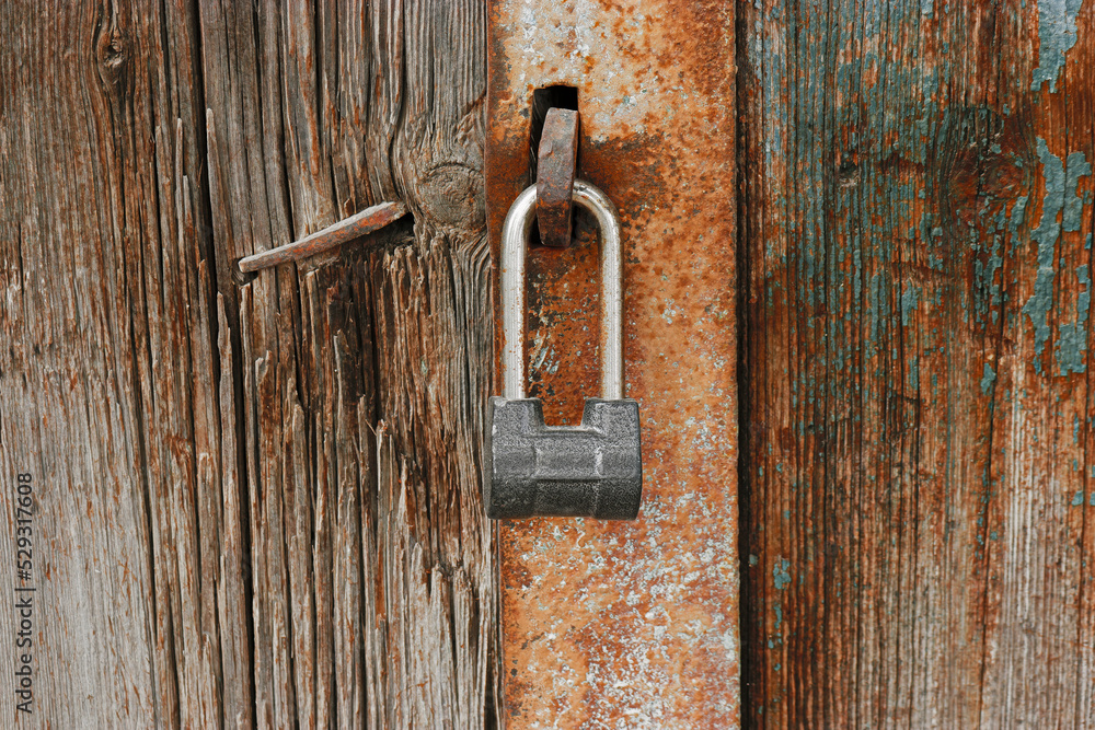 Old padlock on gates. A lock hangs on the wooden door Old padlock on gates. A lock hangs on the wooden door