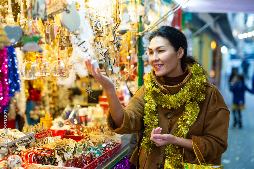Smiling asian woman customer near counter with Christmas gifts at Christmas market