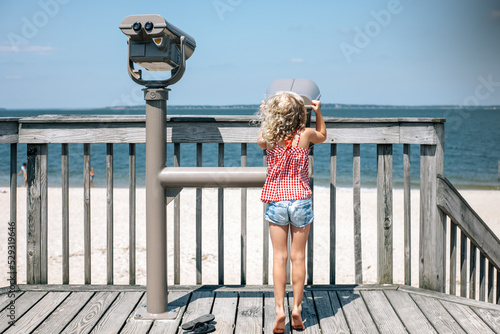 young girl with blonde hair looking out over the ocean in sag harbor photo