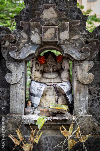 Offering at a Small Sculpture at a Temple in Bali, Indonesia photo