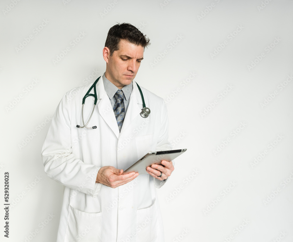 Medical doctor in white coat looking at tablet on white background. Medical doctor in white coat looking at tablet on white background.