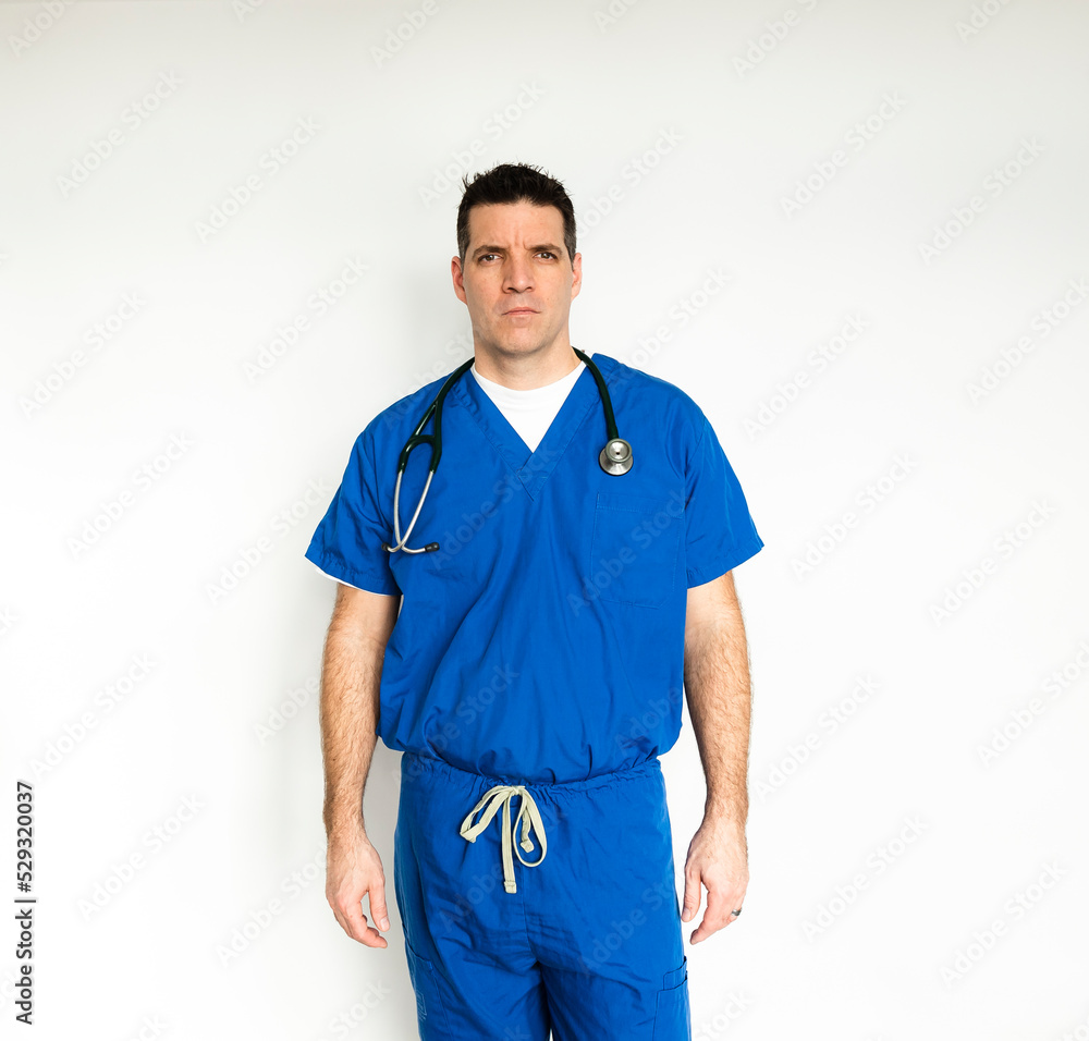 Medical doctor in surgical scrubs standing against a white backdrop. Medical doctor in surgical scrubs standing against a white backdrop.