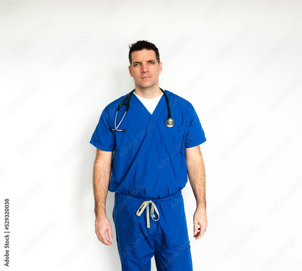 Medical doctor in surgical scrubs standing against a white backdrop. Medical doctor in surgical scrubs standing against a white backdrop.