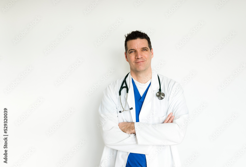 Medical doctor in white coat and scrubs standing with arms folded. Medical doctor in white coat and scrubs standing with arms folded.