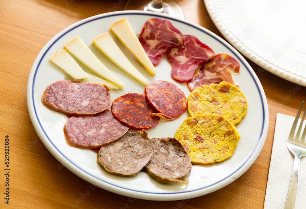 Traditional spanish snack tapas on a plate, selection of ham, salami and cheese