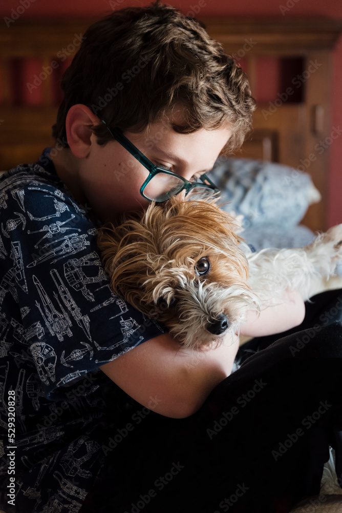 Tween sitting on a bed kissing his Yorkshire Terrier. Tween sitting on a bed kissing his Yorkshire Terrier.