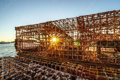 Sunrise starburst behind lobster traps on dock in Bar Harbor, Maine