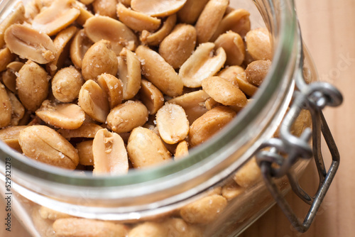 Open canning jar with fried salty peanuts. Selective focus. High angle photo