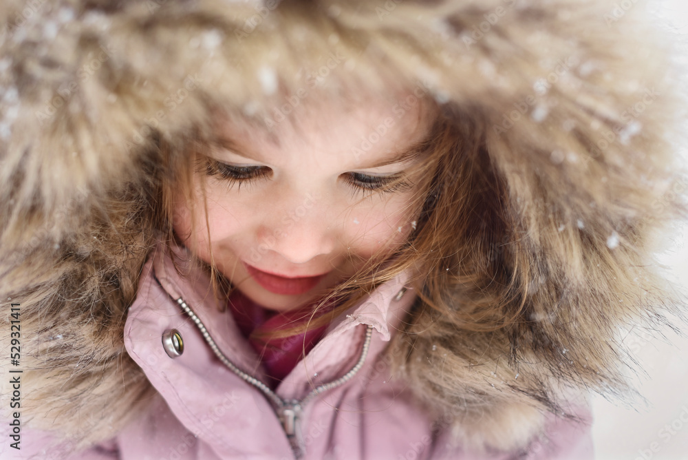 Close up of child's face in snow as snowflakes land in her hair Close up of child's face in snow as snowflakes land in her hair