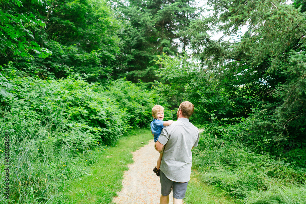 Rear view of a father carrying his young son on a hike Rear view of a father carrying his young son on a hike
