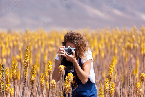 Girl taking picture with film camera in aloe vera field, Fuerteventura photo