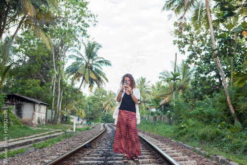 Caucasian girl taking picture with smartphone on train tracks Sri Lank