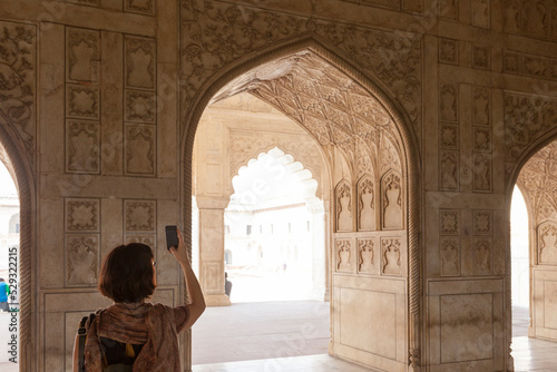 30 years old girl taking photo with smartphone in Agra Fort, India photo