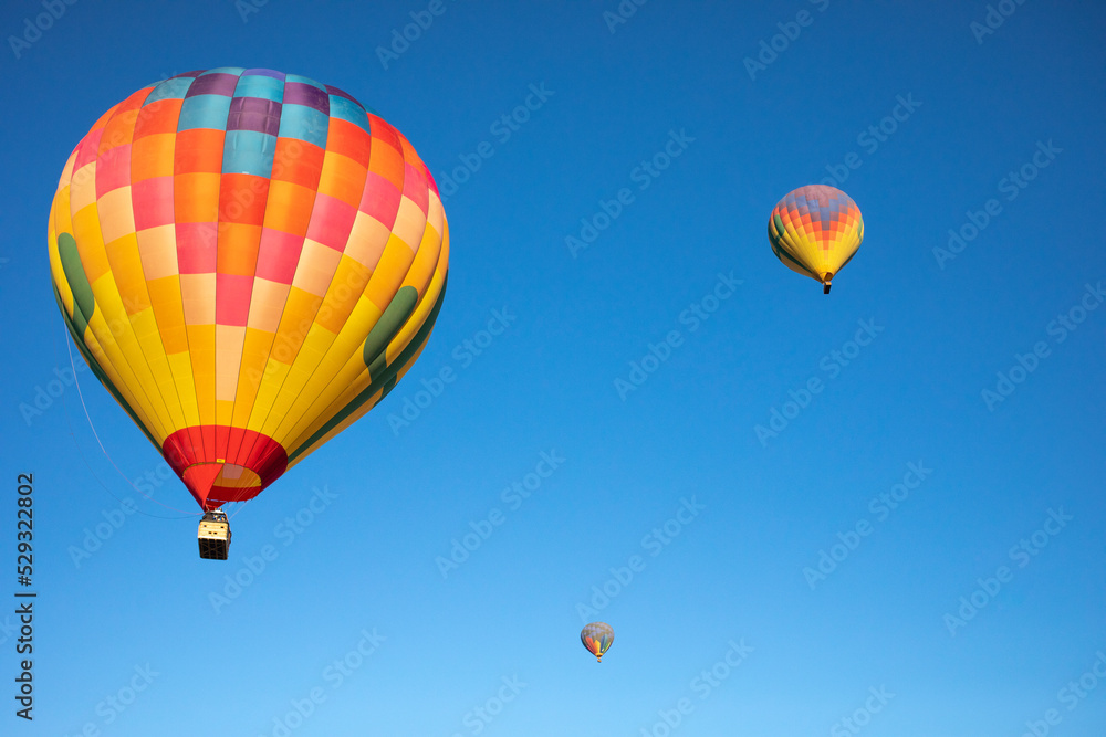 A trio of hot air balloons suspended under a clear blue sky A trio of hot air balloons suspended under a clear blue sky