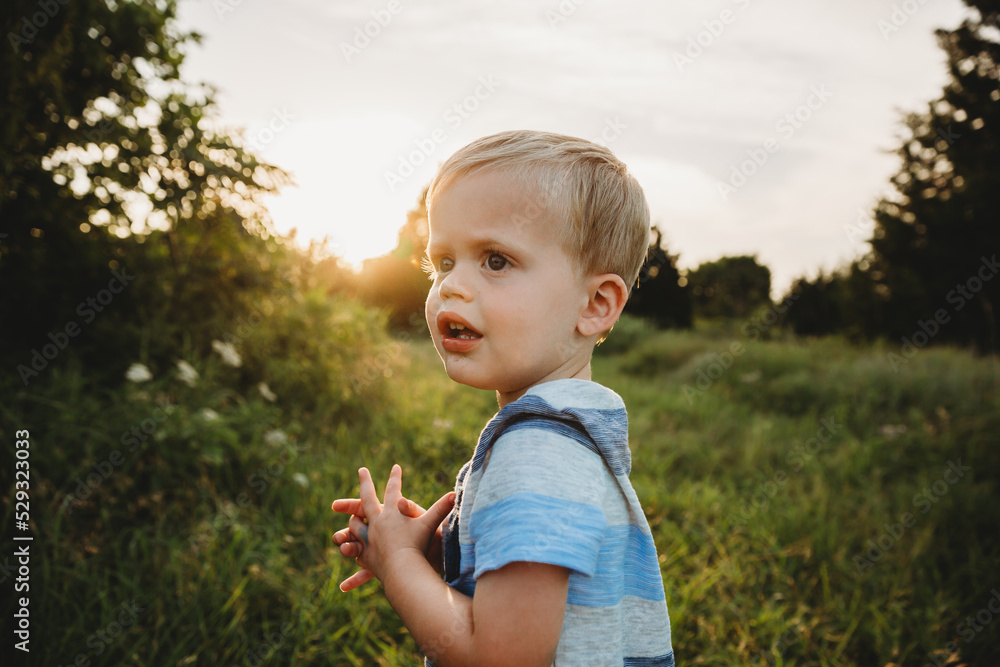Side view of young boy in field at sunset Side view of young boy in field at sunset