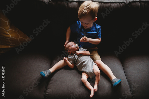 Big brother sitting with newborn brother on couch