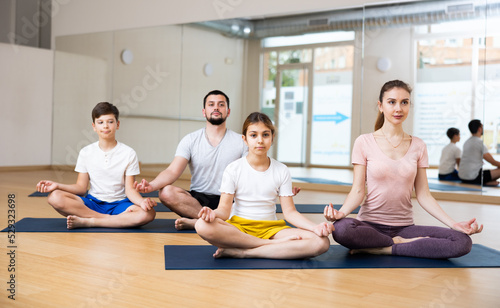 Teen girl and boy exercising with mother and father at couple yoga class, family practicing self-care © JackF
