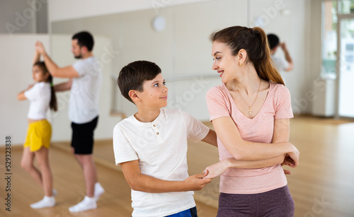 Family practicing dance in pair, positive woman with boy performing pair dance movements