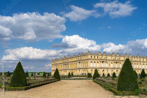 View of part of the facade of the Palace of Versailles and the road leading to it with shrubs trimmed with cones, the historical and architectural heritage of France, the royal residence.