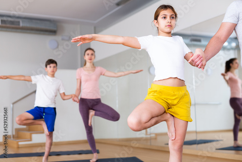 Tween girl exercising with brother, mother and father at yoga class, concept of healthy family lifestyle