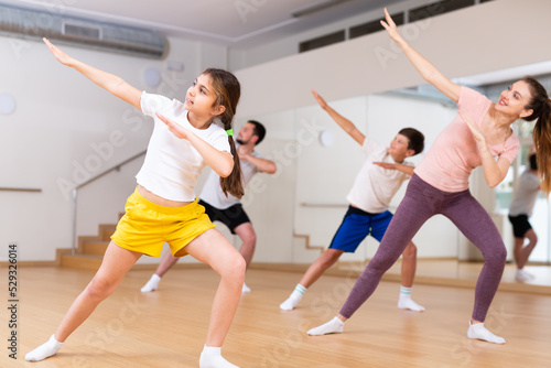 Portrait of tween girl doing exercises during family class in dance center