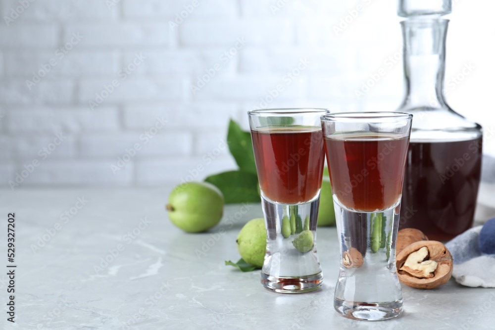 Delicious liqueur and fresh walnuts on light grey table. Space for text Delicious liqueur and fresh walnuts on light grey table. Space for text