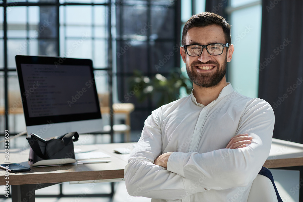 Portrait of young smiling cheerful businessman in office looking Portrait of young smiling cheerful businessman in office looking
