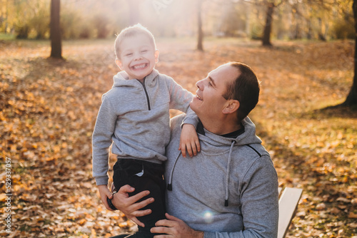 Father carrying his son in his arms enjoying the time spent together between father and son, happy child toothy smiling. Autumn forest. Parent, child. Happy © Strelciuc