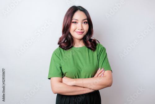 Portrait of a confident smiling Asian woman standing with arms folded and looking at the camera isolated over white background © Reezky