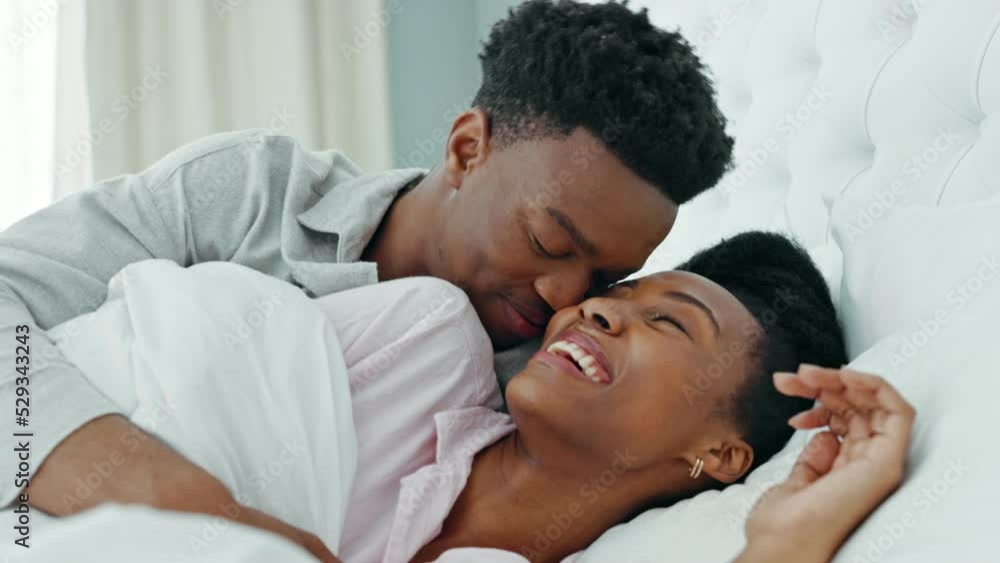 Kissing, morning and couple in bed waking up together in a luxury hotel bedroom or getaway honeymoon retreat. Love, care and happy man, woman or black people cuddle under blankets bonding on weekend Kissing, morning and couple in bed waking up together in a luxury hotel bedroom or getaway honeymoon retreat. Love, care and happy man, woman or black people cuddle under blankets bonding on weekend