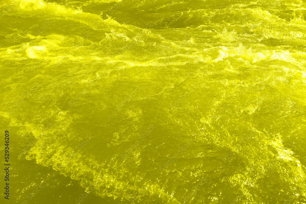 Defocus blurred transparent yellow colored clear calm water surface texture with splash, bubble. Shining yellow water ripple background. Surface of water in swimming pool. Yellow bubble water, splash. Defocus blurred transparent yellow colored clear calm water surface texture with splash, bubble. Shining yellow water ripple background. Surface of water in swimming pool. Yellow bubble water, splash.