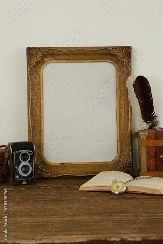 Photo frame, camera, clock and book on table