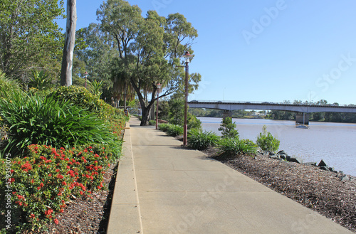 View of the Rockhampton waterfront with plants, walkway, trees, Fitzroy River and bridge in Queensland, Australia